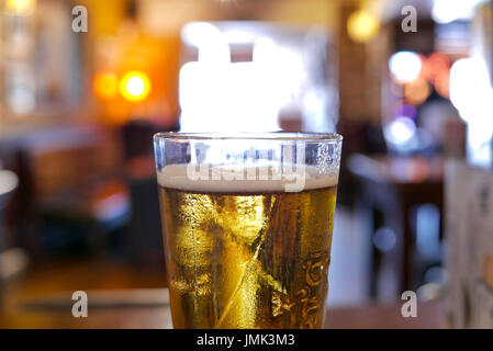 Verre de bière blonde s'assit sur un bar contre la lumière d'une fenêtre.hors focus contexte Banque D'Images