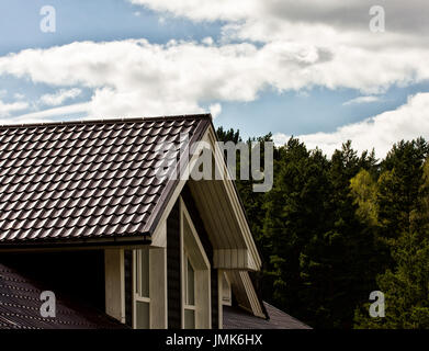 Partie d'une maison en bois, le toit et le ciel avec des nuages Banque D'Images