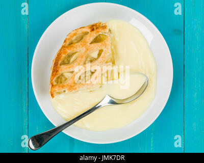 Tarte aux pommes et crème anglaise dessert against a blue background Banque D'Images