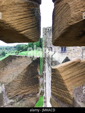 Une vue de l'archer par la flèche le long de la fente d'un des murs en pierre crénelée Norman château d'Angleterre. Banque D'Images