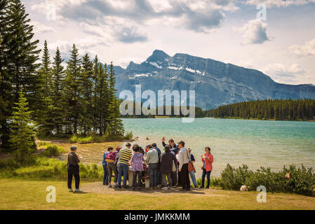 Groupe de touristes asiatiques en train de dîner les deux jack Lake dans le parc national de Banff avec Mt. Rundle en arrière-plan. Banque D'Images