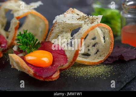 Viande séchée sur du pain croustillant avec œuf et fromage, parmegano fermer, selective focus Banque D'Images