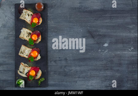 Quatre petits apéritifs avec guéri a rencontré, œuf et fromage sur parmegano avec pierre copyspace. Vue d'en haut Banque D'Images
