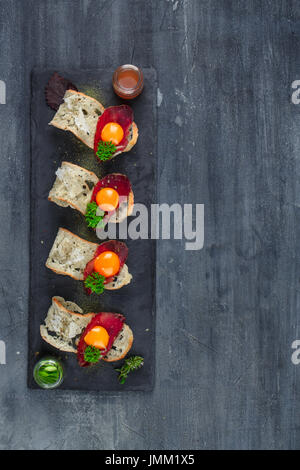 Quatre petits apéritifs avec guéri a rencontré, œuf et fromage sur parmegano avec pierre copyspace. Vue d'en haut Banque D'Images