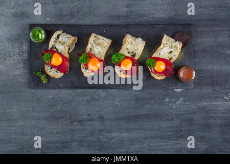 Quatre petits apéritifs avec guéri a rencontré, œuf et fromage sur parmegano avec pierre copyspace. Vue d'en haut Banque D'Images