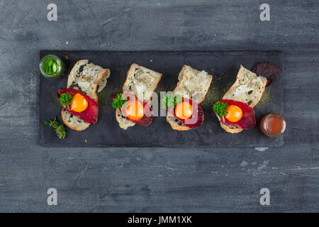 Quatre petits apéritifs avec guéri a rencontré, œuf et fromage sur parmegano avec pierre copyspace. Vue d'en haut Banque D'Images