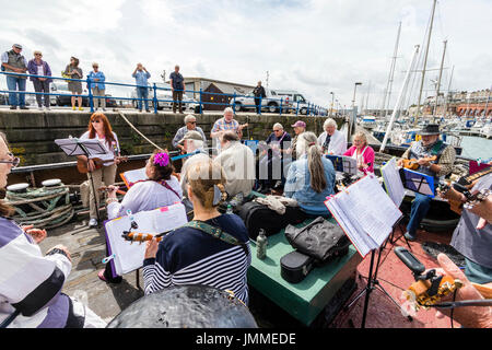 Concert par l'accord groupe, The Sunshine Ukes sur le dos d'un remorqueur, le Cervia, ancrés dans le port au cours de la fête de Ramsgate. Principalement des aînés, hommes et femmes, assis sur le pont arrière du bateau. Banque D'Images