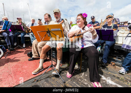 Concert par l'accord groupe, The Sunshine Ukes sur le dos d'un remorqueur, le Cervia, ancrés dans le port au cours de la fête de Ramsgate. Principalement des aînés, hommes et femmes, assis sur le pont arrière du bateau. Banque D'Images