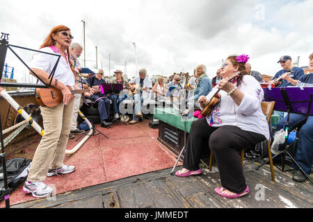 Concert par l'accord groupe, The Sunshine Ukes sur le dos d'un remorqueur, le Cervia, ancrés dans le port au cours de la fête de Ramsgate. Principalement des aînés, hommes et femmes, assis sur le pont arrière du bateau. Banque D'Images