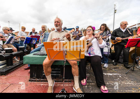 Concert par l'accord groupe, The Sunshine Ukes sur le dos d'un remorqueur, le Cervia, ancrés dans le port au cours de la fête de Ramsgate. Principalement des aînés, hommes et femmes, assis sur le pont arrière du bateau. Banque D'Images