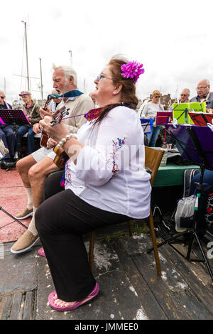 Concert par l'accord groupe, The Sunshine Ukes sur le dos d'un remorqueur, le Cervia, ancrés dans le port au cours de la fête de Ramsgate. Principalement des aînés, hommes et femmes, assis sur le pont arrière du bateau. Banque D'Images