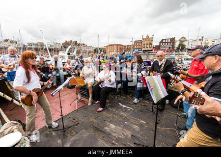 Concert par l'accord groupe, The Sunshine Ukes sur le dos d'un remorqueur, le Cervia, ancrés dans le port au cours de la fête de Ramsgate. Principalement des aînés, hommes et femmes, assis sur le pont arrière du bateau. Banque D'Images