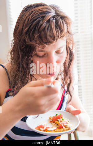 Closeup portrait of young woman eating et à mâcher oignon apéritif sain sur pain plat salade avec toast chia fork Banque D'Images