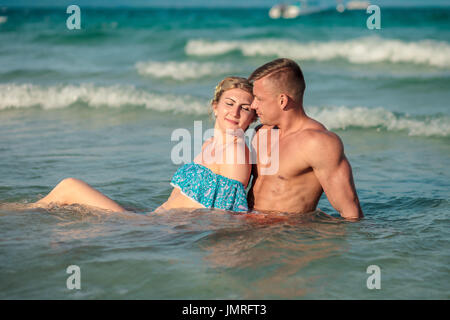 Heureux couple hugging en même temps dans l'eau de mer sur la plage Banque D'Images
