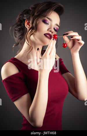 Fille élégante en robe rouge cerise avec dans les mains Banque D'Images