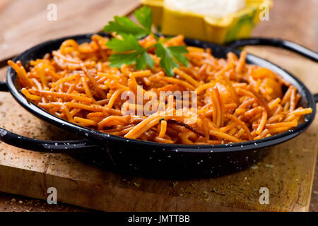 Libre d'une fideua typique espagnol, une casserole de nouilles aux fruits de mer, paella dans une casserole et sauce aïoli dans un mortier jaune sur une table en bois rustique Banque D'Images