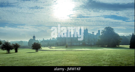 Burghley House du Lincolnshire prises par un froid matin d'automne précoce, le lever du soleil dans l'arrière-plan et la rosée du matin sur les pelouses. Banque D'Images