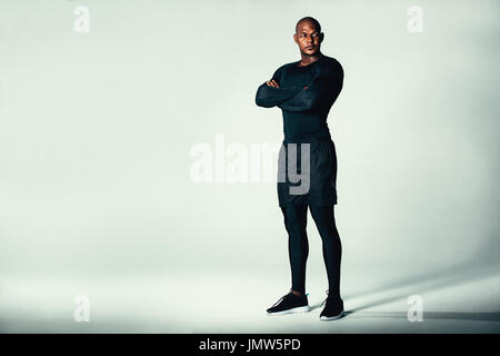 Portrait de l'aptitude des hommes à la sportswear avec ses bras croisés. Male bodybuilder debout sur fond gris et à la voiture. Banque D'Images