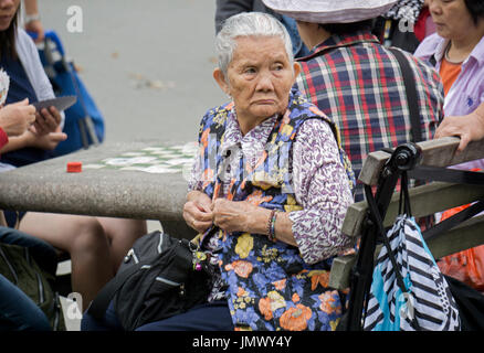 Une vieille femme chinoise à une table pour un seul jeu de cartes dans Columbus Park dans le quartier chinois, la ville de New York. Banque D'Images