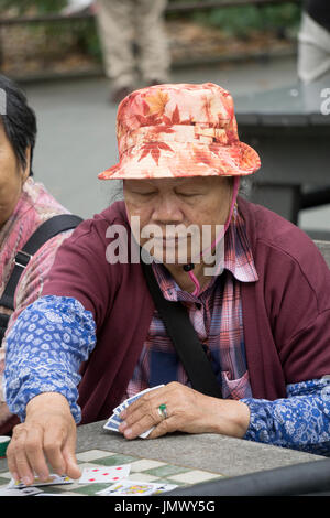 Une vieille femme chinoise cartes à jouer dans un seul jeu des femmes dans Columbus Park dans le quartier chinois, la ville de New York. Banque D'Images