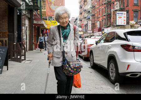 Une vieille femme chinoise à l'extérieur du shopping sur une journée d'été sur Mott Street à Chinatown, Lower Manhattan, New York City Banque D'Images