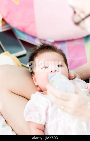 Portrait d'un adorable petit bébé fille bébé allongé sur le dos et de l'alimentation Banque D'Images