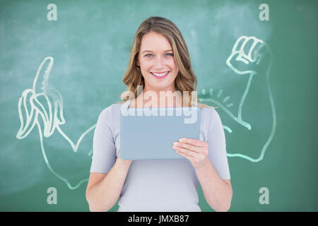 Smiling teacher using digital tablet in front of blackboard à l'image numérique de hand holding banana Banque D'Images