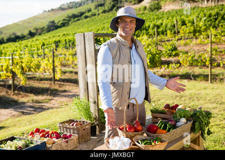 Portrait of happy man standing at vegetable stall in vineyard Banque D'Images