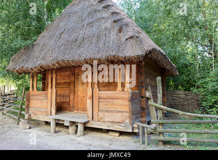 Ancienne grange rural ukrainien traditionnel avec un toit de chaume et un en bois, barrière autour de lui dans un jardin verdoyant Banque D'Images