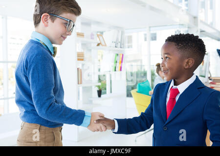 Les enfants comme les dirigeants d'shaking hands in office Banque D'Images