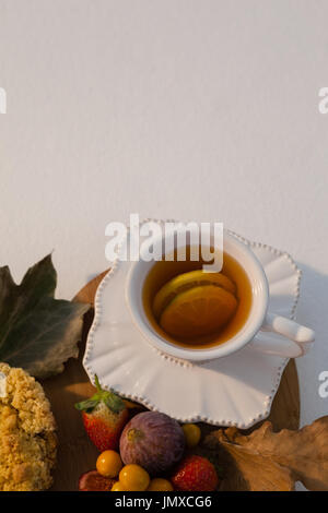 Les frais généraux de divers fruits, feuilles d'automne et tasse de thé vert sur planche à découper Banque D'Images