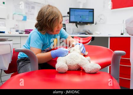 Enfant à l'usage éditorial du dentiste seul modèle publié. Enfant at dentist's avec nounours. Banque D'Images