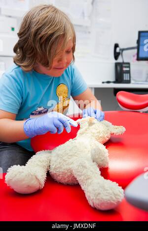 Enfant à l'usage éditorial du dentiste seul modèle publié. Enfant at dentist's avec nounours. Banque D'Images