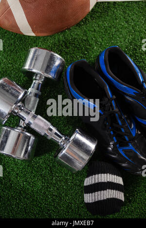 Portrait d'haltères par la chaussure de sport et sur le terrain de football américain Banque D'Images