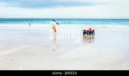 Un sauveteur sur la plage de St Ives, Cornwall définissant un drapeau de surf Banque D'Images