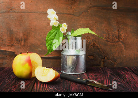 La nature morte d'un brin de jasmin fleurs dans un seau en métal. Anime une photo de tranches de pomme et un gâteau avec le couteau fourche Banque D'Images