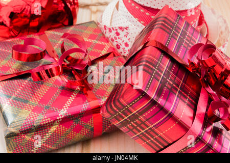 Deux cadeaux de Noël enveloppé en rouge et or papier cadeau brillant avec rubans cadeaux à l'arrière. Banque D'Images