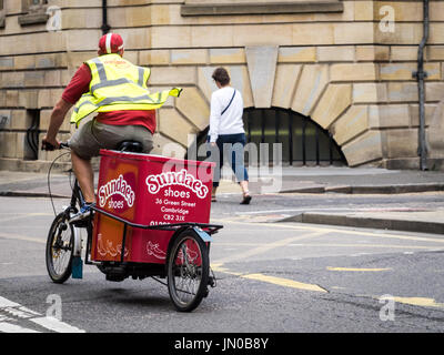 Un cavalier et vélo de cargaison appartenant à l'entreprise de livraison du dernier kilomètre franc stationné dans le centre historique de Cambridge, au Royaume-Uni. Banque D'Images