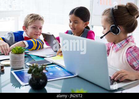 Les enfants comme les cadres travaillant ensemble dans office Banque D'Images