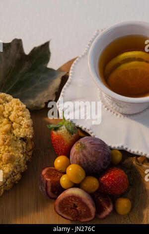 Les frais généraux de divers fruits, feuilles d'automne et tasse de thé vert sur planche à découper Banque D'Images