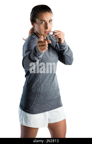 Portrait d'entraîneur féminin désignant tout en soufflant sifflent contre fond blanc Banque D'Images