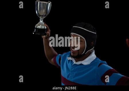 High angle view of rugby player holding trophy sur fond noir Banque D'Images