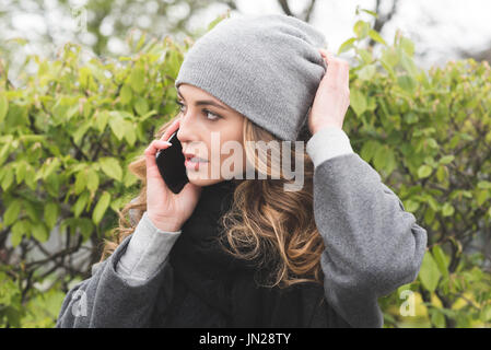 Femme à la voiture tout en parlant au téléphone en stationnement pendant l'hiver Banque D'Images