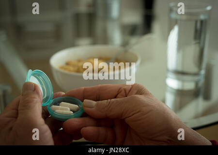 La main coupée de woman holding pill bottle at table Banque D'Images