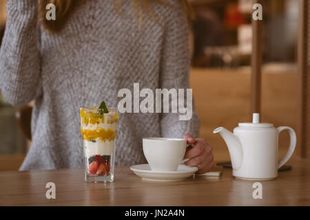 La mi-section of woman holding Coffee cup dans le café Banque D'Images