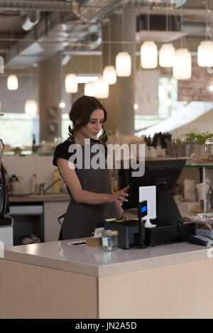 Femme propriétaire à l'aide d'espèces compteur dans cafe Banque D'Images