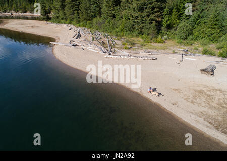 Woman relaxing with dog sur la rive du lac sur une journée ensoleillée Banque D'Images