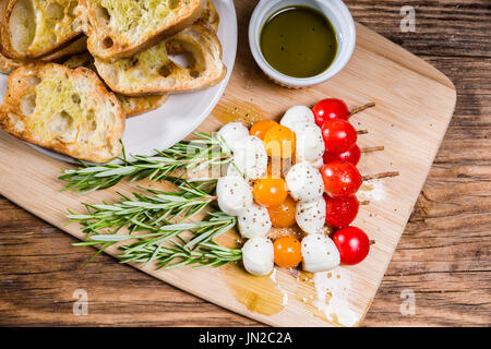 Fromage et pain tomate bouchées sur des brochettes de romarin Banque D'Images