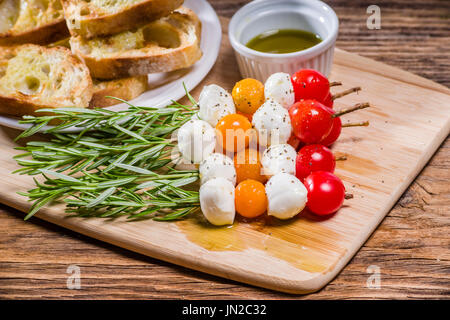 Fromage et pain tomate bouchées sur des brochettes de romarin Banque D'Images