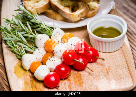 Fromage et pain tomate bouchées sur des brochettes de romarin Banque D'Images